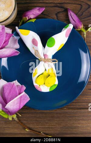 Petite figurine de lapin blanc avec œufs de Pâques blancs et orchidées et fleurs roses sur fond de bois rustique. Banque D'Images