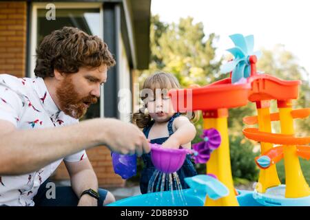 Père et petite fille (2-3) jouant avec l'eau dans le jardin Banque D'Images