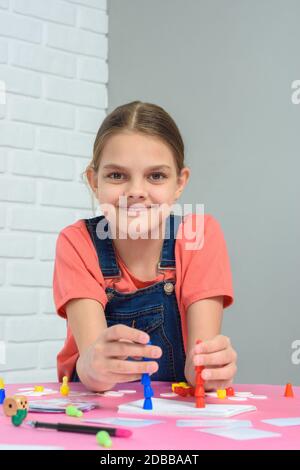 Fille joue à des jeux de société, se trouve à une table à la maison Banque D'Images