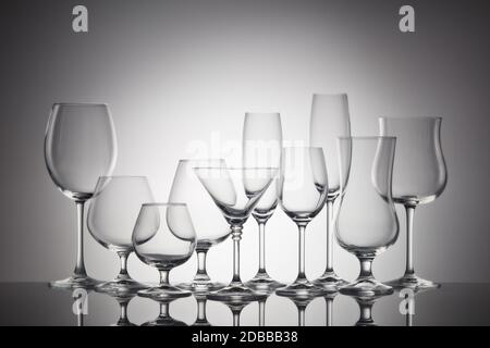 Ensemble de verres pour différentes boissons alcoolisées et cocktails sur fond gris foncé. Vider la verrerie transparente. Banque D'Images