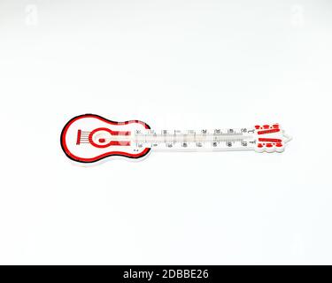 Thermomètre à alcool à échelle rouge. Thermomètre en forme de guitare sur fond blanc. Banque D'Images