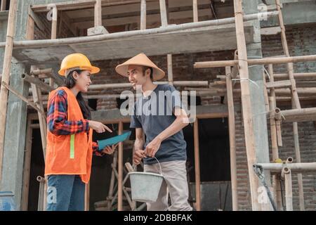 discussion entre l'entrepreneur et le constructeur au sujet des esquisses de bâtiment dans le bâtiment arrière-plan de la construction Banque D'Images