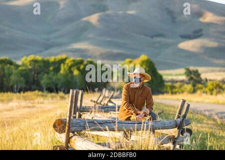 États-Unis, Idaho, Bellevue, Rancher dans le masque de visage appuyé contre la clôture sur le terrain Banque D'Images