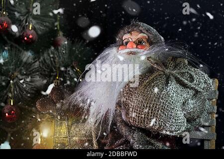 Le Père Noël en plein air à côté d'arbre de Noël dans la neige transportant des cadeaux aux enfants. Joyeux Noël & Nouvel An concept Banque D'Images