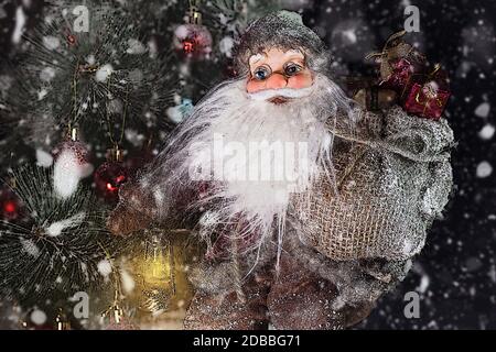 Le Père Noël en plein air à côté d'arbre de Noël dans la neige transportant des cadeaux aux enfants. Joyeux Noël & Nouvel An concept Banque D'Images