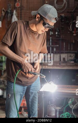 Les soudeurs se tiennent debout en portant des lunettes de soudage noires lors de la fabrication du métal dans un atelier de soudage Banque D'Images