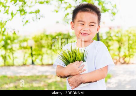 Journée mondiale de l'environnement Environnement et Save World concept, main de l'asiatique mignon petit garçon gai petit enfant tenant jeune arbre sur le pot blanc sur le jardin vert Banque D'Images