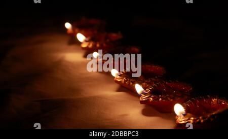 Lampes traditionnelles indiennes en argile avec des flammes vives maintenues ensemble dans une rangée pendant les célébrations du festival culturel hindou indien de diwali ou puja. Banque D'Images