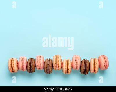 Macarons avec espace de copie. Rangée de macarons ou macarons français parfaits sur fond bleu. Vue de dessus ou plat Banque D'Images