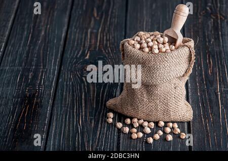 Sac avec pois chiches et cuillère sur fond en bois Banque D'Images