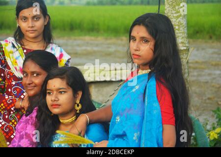 Gros plan de quatre jeunes filles bengali indiennes portant une saree traditionnelle et des bijoux comme un collier doré, des boucles d'oreilles, une pointe de nez avec de longs cheveux foncés Banque D'Images