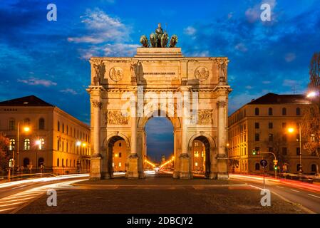 Siegestor (porte de la victoire) dans la soirée. Flou de mouvement des feux de voiture en raison d'une longue exposition. Munich, Bavière, Allemagne Banque D'Images