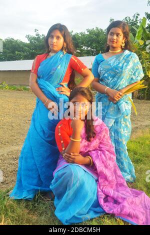 Trois jeunes filles de village portant une robe traditionnelle bengali indienne et posant pour la caméra dans un champ de village, focalisation sélective Banque D'Images