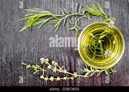 Cadre avec tisane dans une tasse de verre, branches d'estragon, romarin et thym sur fond de bois de dessus Banque D'Images