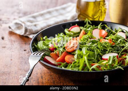 Salade d'arugula fraîche avec des radis, des tomates et des poivrons rouges sur plaque. Banque D'Images