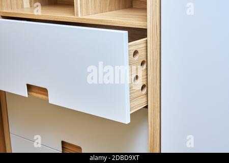 Détail de la garde-robe en gros plan. armoire moderne avec tiroirs en bois ouverts. armoire en bois avec portes de garde-robe plates à tirer sur les doigts. Plywoo plaqué chêne Banque D'Images