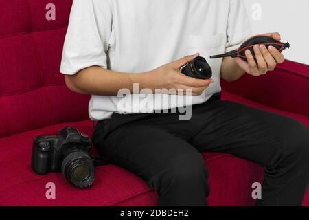 Un photographe asiatique nettoie l'appareil photo et l'objectif avec un appareil photo à soufflerie d'air pour la prise de vue de modèles de mode en studio. Banque D'Images