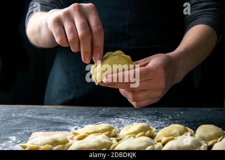 Faire cuire dans un blouson foncé préparer les boulettes. Sur une table sombre sur laquelle les boulettes finies sont disposées. Vues de face, gros plan. Banque D'Images