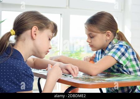 Deux filles collectent avec enthousiasme des puzzles à la table à la maison Banque D'Images