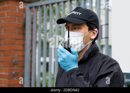 Garde de sécurité dans masque de visage parlant sur Talkie Walkie Banque D'Images