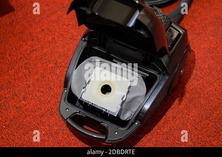 Un aspirateur avec un jeu de brosses et de sacs. Un aspirateur sur le tapis rouge. Banque D'Images