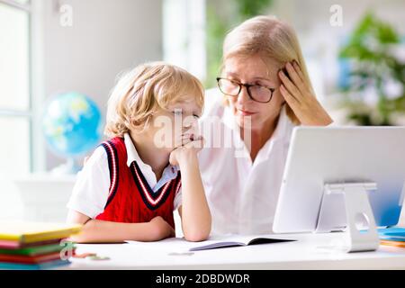 Apprentissage à distance en ligne. Les enfants de l'école avec ordinateur ayant la vidéo conférence chat avec le professeur et le groupe de classe. Mère aidant son. Banque D'Images