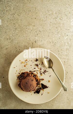 Cuillère à crème glacée aux saveurs de chocolat, décorée de morceaux de chocolat et de noix sur l'assiette Banque D'Images