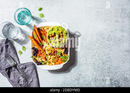 Concept de cuisine végétarienne. Légumes cuits au four avec houmous verts, fond clair. Nourriture saine d'été. Banque D'Images