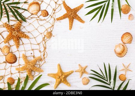 Concept de l'heure d'été avec des coquillages de mer et des étoiles de mer sur un fond en bois blanc. Banque D'Images