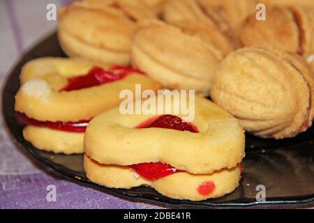 Biscuits aux noix et au cœur. Pâtisserie en forme de coeurs et de huttes avec garniture douce. Confiseries sucrées Banque D'Images