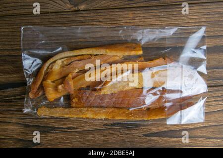 Calmar péruvien dans un emballage transparent sur fond en bois. En-cas sur le poisson avec de la bière. Gros plan. Banque D'Images