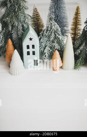Joyeux Noël ! Scène de Noël, village de vacances miniature, espace pour le texte. Noël petites maisons en céramique, bois et sapins enneigés sur le dos blanc Banque D'Images