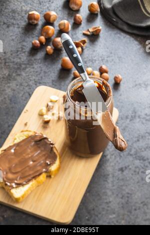 Tartinade aux noisettes et pain grillé. Crème au chocolat sur planche à découper. Banque D'Images