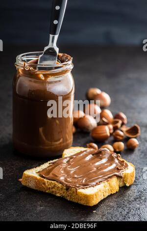 Toaster le pain avec de la pâte de noisette. Crème au chocolat sur une table de cuisine noire. Banque D'Images