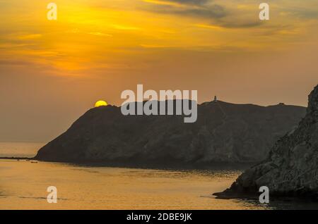 Golden Sun se délpe de derrière une montagne avec un fond de ciel doré à Muscat, Oman. Banque D'Images