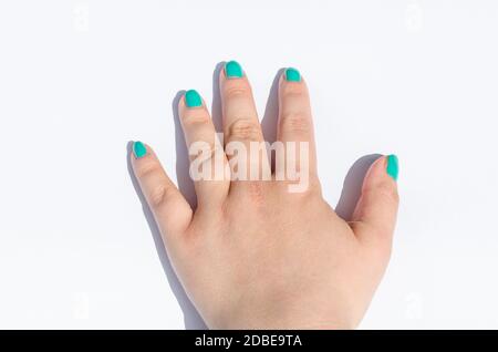 La main féminine avec nail design vert sur fond blanc. Banque D'Images