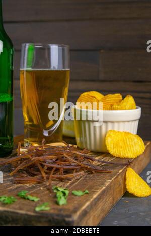 Patates sombres sur un panneau en bois sombre, patates et bière. En-cas sur le poisson avec de la bière. Gros plan. Banque D'Images