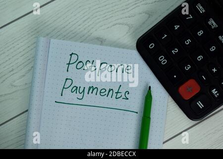 Reporter les paiements écrire sur la note adhésive isolée sur la table en bois. Banque D'Images