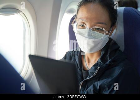 femme asiatique passager assis en cabine de lecture d'avion ebook à l'aide d'un appareil électronique Banque D'Images