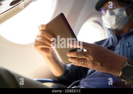 homme asiatique passager assis en cabine de lecture d'avion ebook utilisant e-reader Banque D'Images