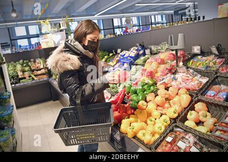 Sujet image pandémie de coronavirus en automne/hiver, jeune femme avec panier shopping dans un supermarché le 17 novembre 2020 à Muenchen - elle se tient devant le comptoir de légumes et porte un masque, un masque. MODÈLE DISPONIBLE ! | utilisation dans le monde entier Banque D'Images