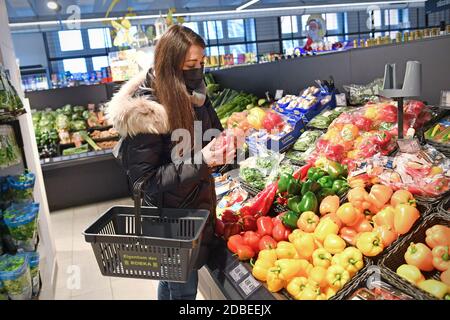 Sujet image pandémie de coronavirus en automne/hiver, jeune femme avec panier shopping dans un supermarché le 17 novembre 2020 à Muenchen - elle se tient devant le comptoir de légumes et porte un masque, un masque. MODÈLE DISPONIBLE ! | utilisation dans le monde entier Banque D'Images