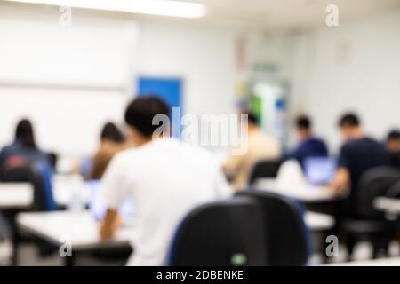 salle de classe floue étudiants d'université assis avec des ordinateurs dans la salle de conférence, séminaire ou salle de réunion / conférence avec un enseignant, tableau blanc / diapositive scr Banque D'Images