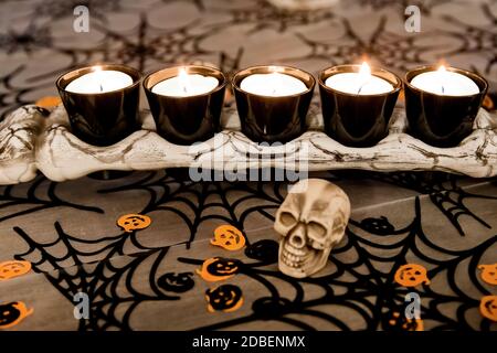 Un os avec des bougies chauffe-plat, des crânes au premier plan et une bordure d'Halloween Banque D'Images