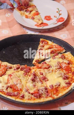 Tranches de pizza fraîche appétissante avec de délicieux ingrédients sur une assiette noire. Pizza savoureuse sur plaque isolée sur la cuisine. Plats chauds Banque D'Images