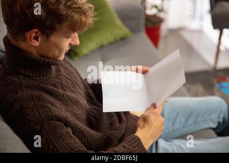 Confortable. Homme ouvrant, recevoir une carte de vœux pour le nouvel an et Noël 2021 de la part d'amis ou de la famille. Lecture d'une lettre avec de meilleurs voeux, ouverture de l'enveloppe. Vacances, fête. Banque D'Images