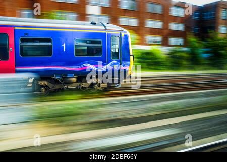 Train bleu anglais en mouvement avec effet diffus lorsqu'il traverse une zone urbaine. Banque D'Images