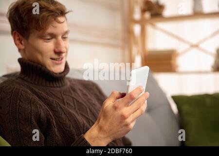 Homme lisant un message, salutations pour le nouvel an et Noël 2021 de ses amis ou de sa famille avec son téléphone portable. Communication à l'aide d'appareils. Vacances, fête. Il a l'air gai, heureux, prudent. Banque D'Images