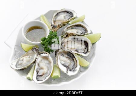 Six huîtres fraîches avec des quartiers de lime et une sauce vinaigrette aux agrumes Banque D'Images