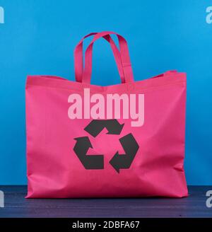 Sac en viscose rose entièrement réutilisable sur fond en bois bleu, concept de réduction des déchets en plastique Banque D'Images